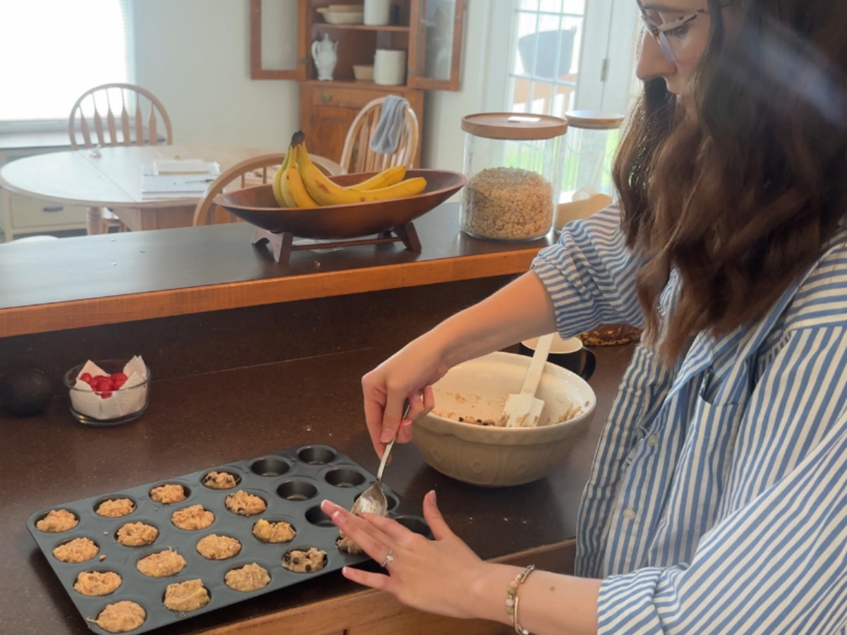 a woman spooning banana muffins into a pan