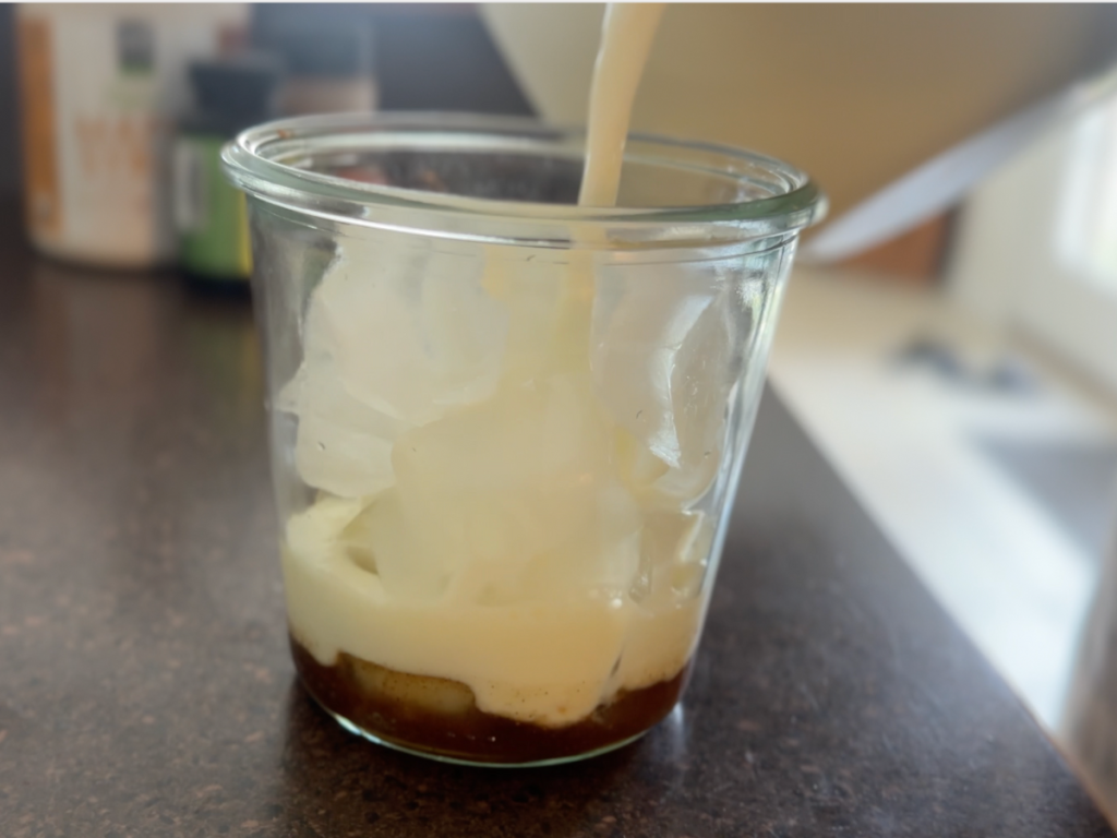 pouring milk into a glass of ice